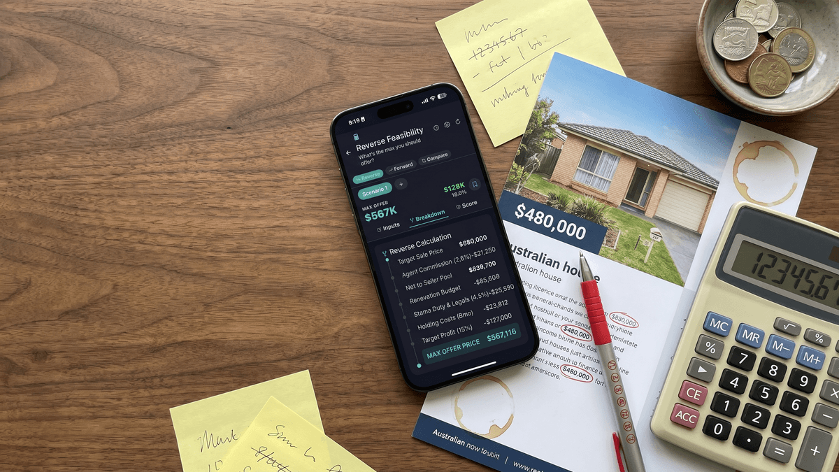 iPhone showing FlipPro's reverse calculation breakdown, on a walnut workbench with a $480,000 property brochure, sticky notes, calculator and a small bowl of coins